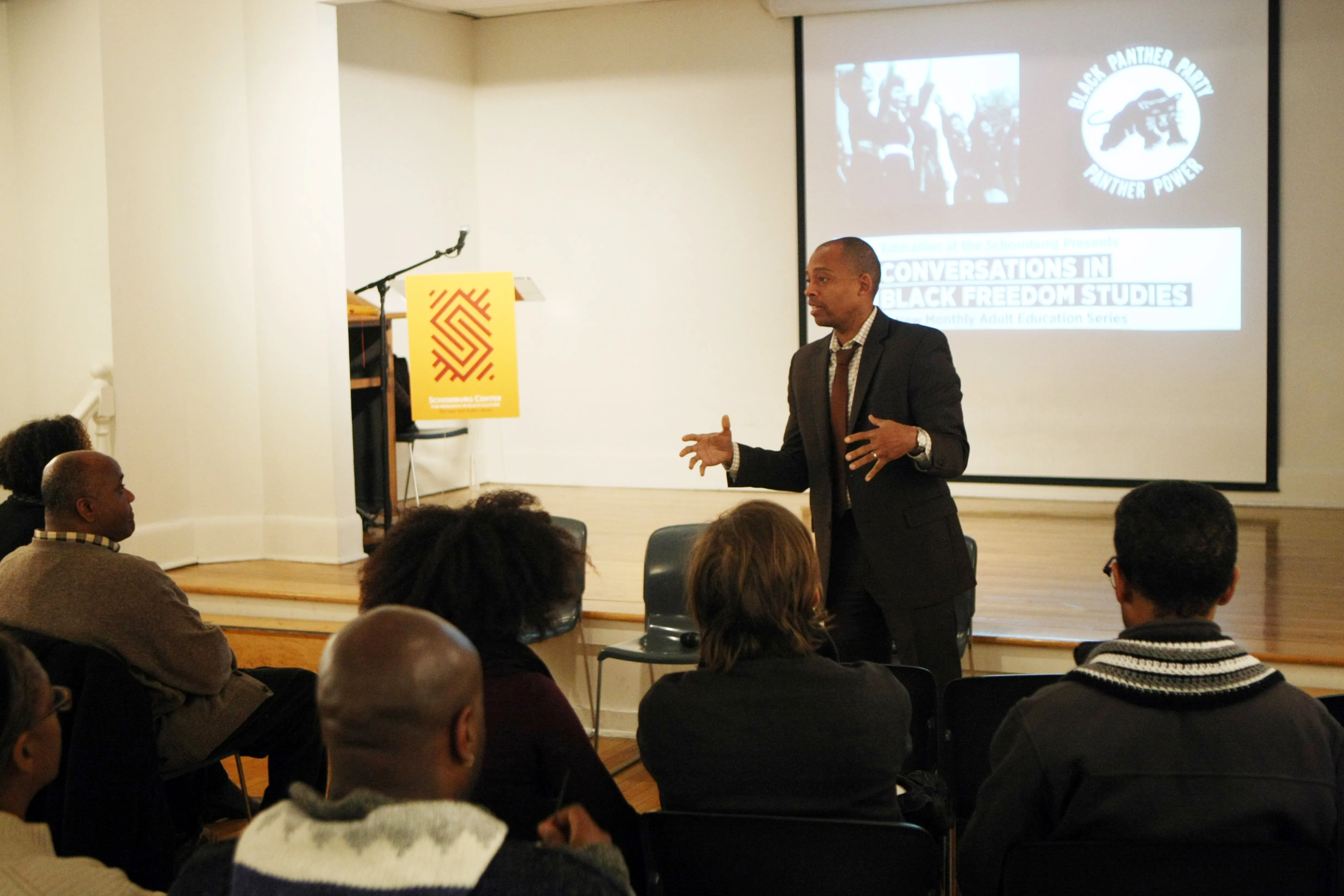 A speaker addresses the audience at a Conversations in Black Freedom Studies event, with a Black Panther Party slide projected behind him